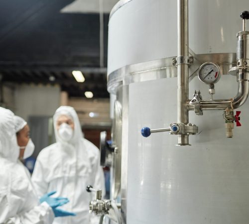 Close up on pressure gauge and pipes on stainless steel tank in workshop of food or chemical factory, copy space